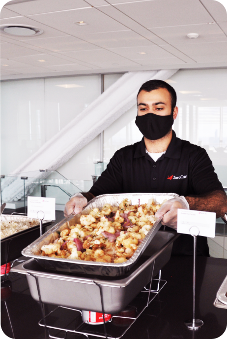 Zerocater employee serving lunch in a metal dish Zerocater employee serving lunch in a metal dish