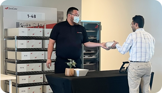 Professional Staff Zerocater staff handing out boxed lunches to an employee