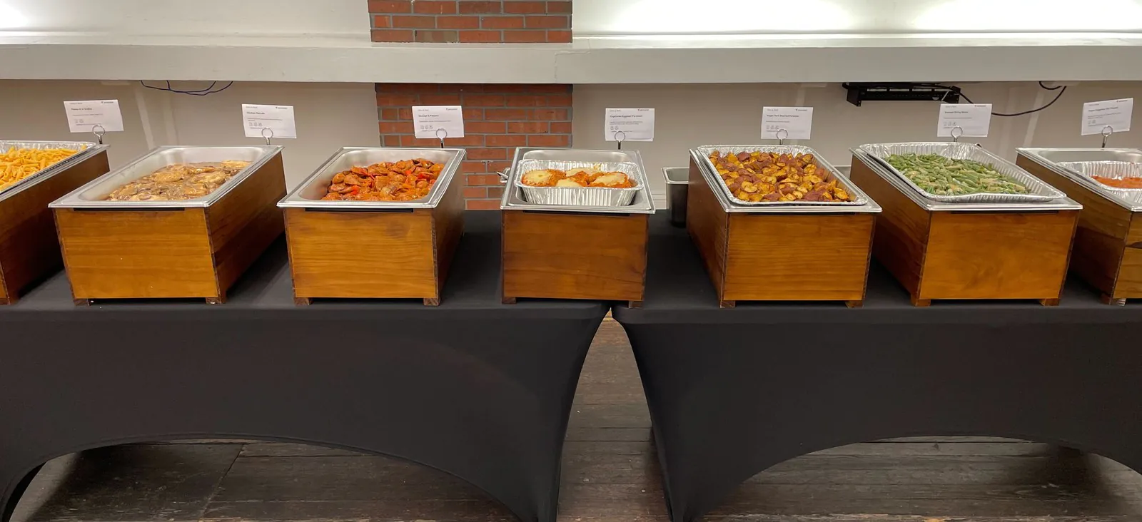 BBQ corporate catering buffet spread with chafing dishes of pulled pork, brisket, and chicken next to classic sides for an office event
