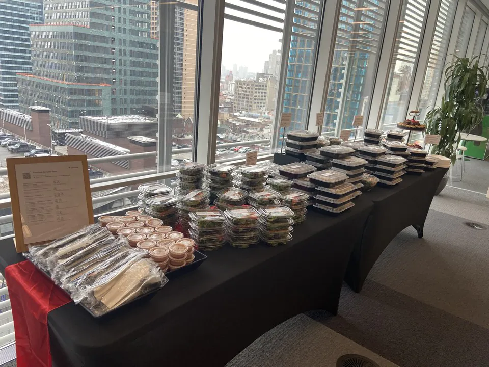 Boxed lunches arranged on a black-draped table with city skyline views