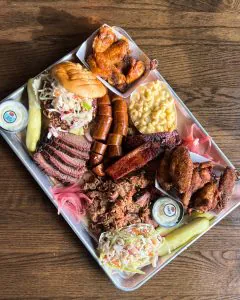 GQue BBQ championship platter with brisket, ribs, chicken, mac and cheese, and coleslaw