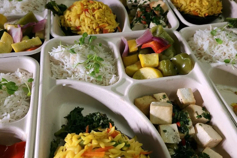 Compartment catering trays with grain salads, marinated tofu, and seasonal vegetables for office boxed lunches