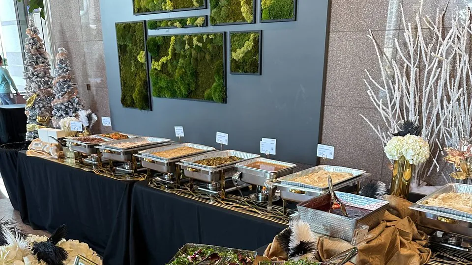 Long buffet line of chafing dishes with white florals and frosted-branch centerpieces for an office holiday party