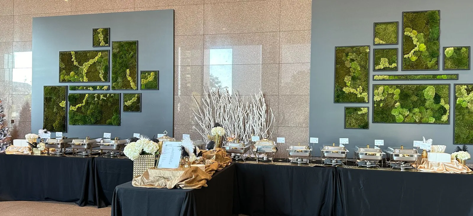 Elegant office holiday party catering buffet with chafing dishes, moss wall art and gold-draped tables in a corporate lobby