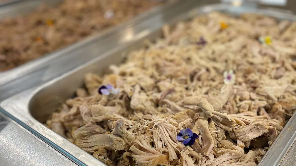 Stainless buffet pan of slow-cooked pulled meat at a Dallas office BBQ catering spread