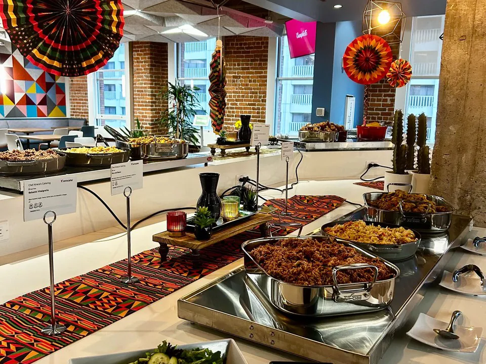 Colorful Denver office buffet with hot entrees in chafing dishes against an exposed-brick wall