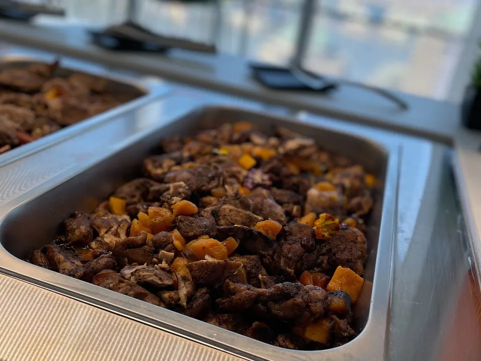 Buffet chafing pan of braised halal chicken with butternut squash on an office buffet line, a hot main for halal catering