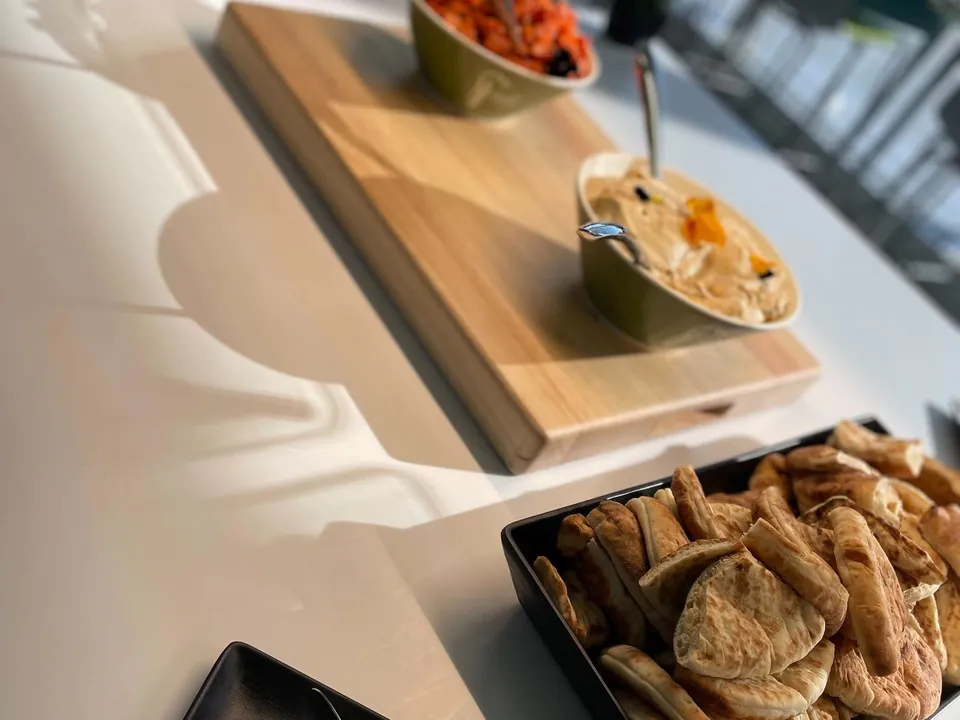 Mezze board with a bowl of hummus, a tomato salad, and a tray of fresh pita, a naturally halal Mediterranean spread for the office