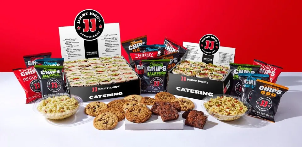 A Jimmy John's catering bundle spread with two catering boxes of subs, assorted Jimmy Chips, cookies, brownies and sides