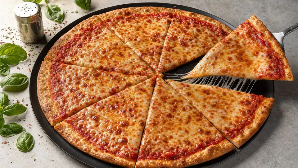 A whole classic New York cheese pizza cut into slices on a black steel pan, with one foldable slice lifted to show the cheese stretch