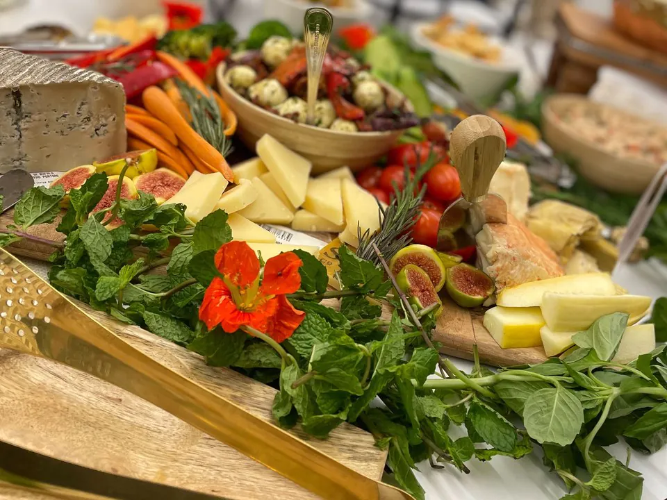 Elegant grazing board with aged cheeses, figs, cured meats, fresh herbs, and edible flowers arranged for a law firm partner event or client reception