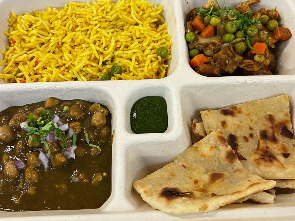 Compartmented boxed meal with rice, chickpea curry, and flatbread for Philadelphia office catering
