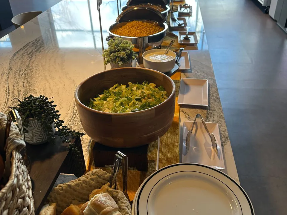 Philadelphia office buffet line with chafing dishes, a salad bowl, and bread on a marble counter
