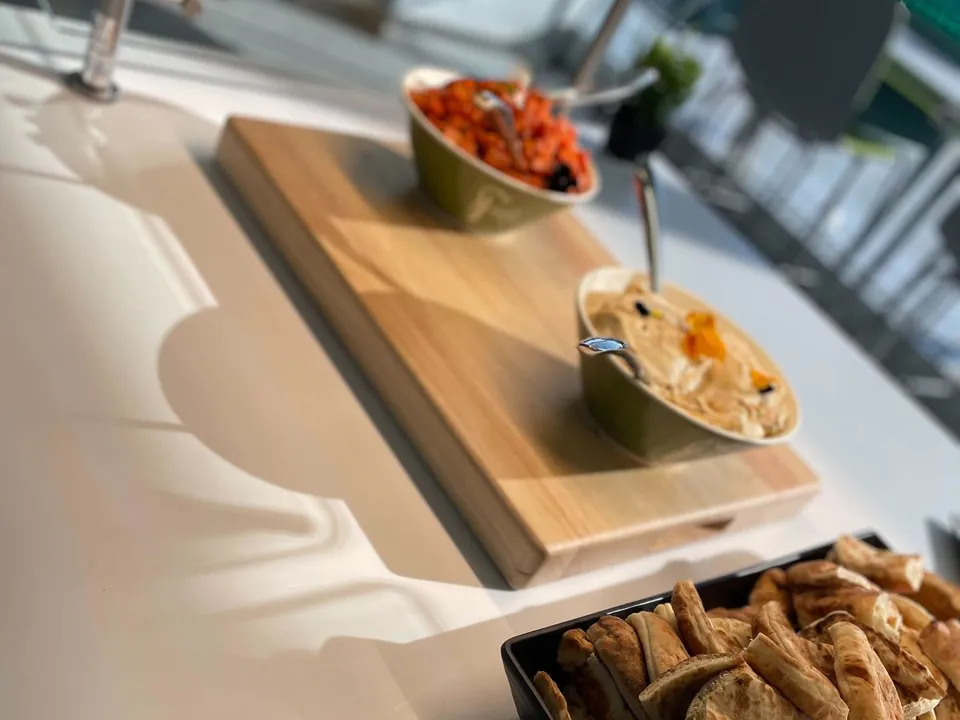 Mediterranean mezze board with a bowl of hummus, a tomato salad, and a tray of freshly sliced pita