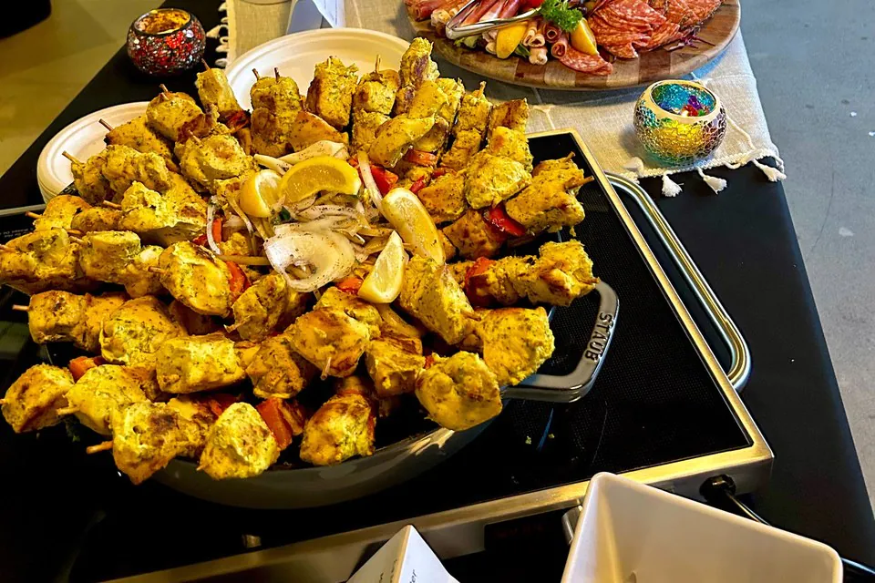 Platter of grilled chicken skewers beside an antipasti and charcuterie board, a keto-friendly office catering spread