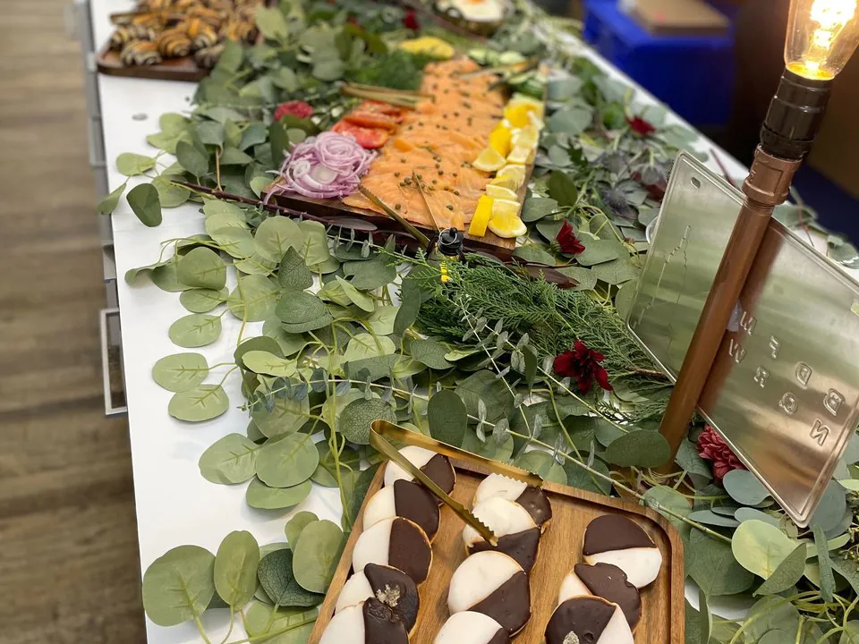 Jewish deli catering spread with a smoked salmon board, black-and-white cookies and babka on an office table