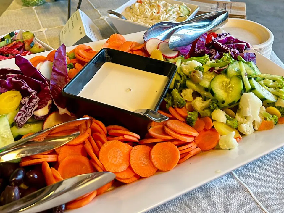 Colorful fresh vegetable crudite platter with carrots, broccoli, cauliflower, tomatoes and dip, a pareve spread for kosher office catering