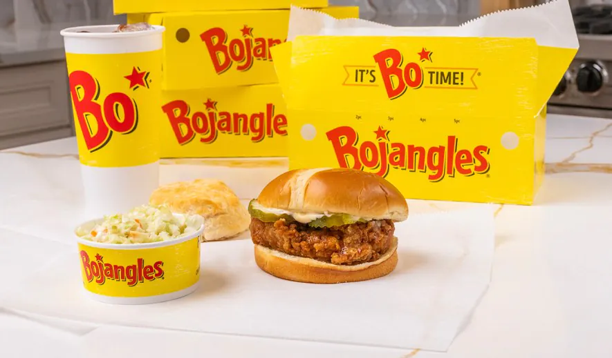Bojangles boxed meal with a chicken sandwich, coleslaw cup, biscuit and drink beside a yellow catering box