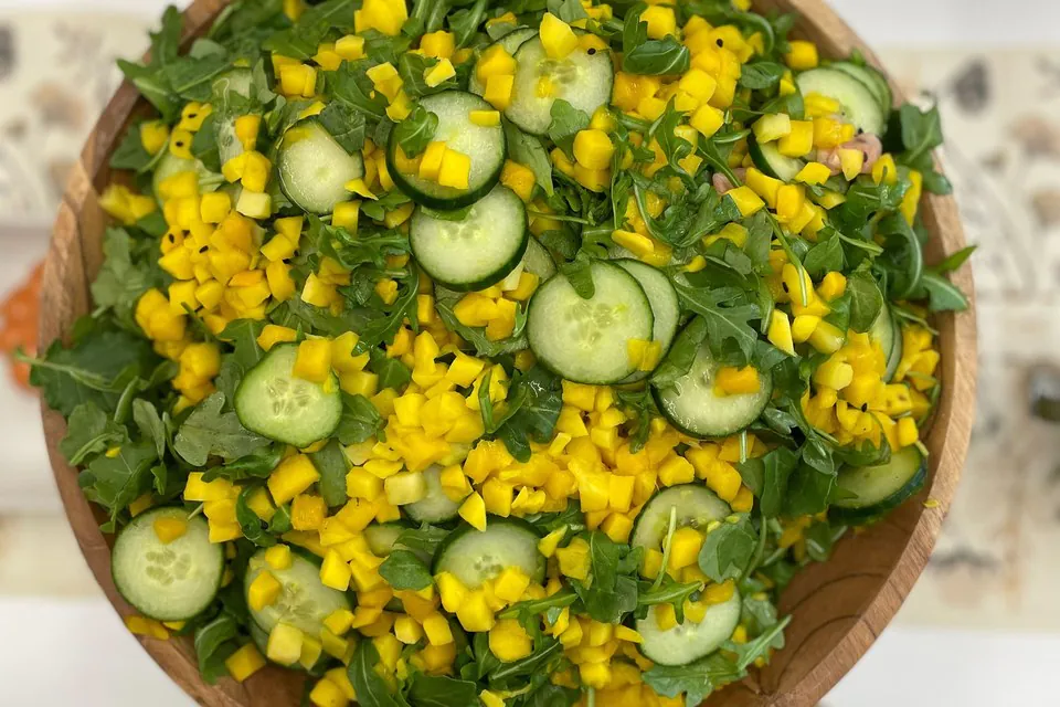 Arugula, diced mango, and cucumber salad dressed with oil instead of a creamy dressing for dairy-free office catering