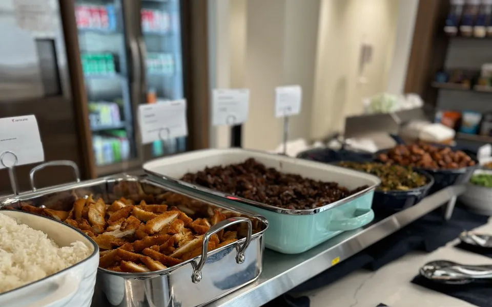 Office buffet line with a tray of breaded chicken, rice and sides along a counter