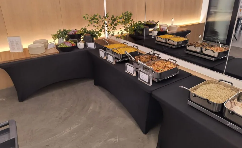 L-shaped buffet of chafing dishes on black-draped tables set up in a hired event room