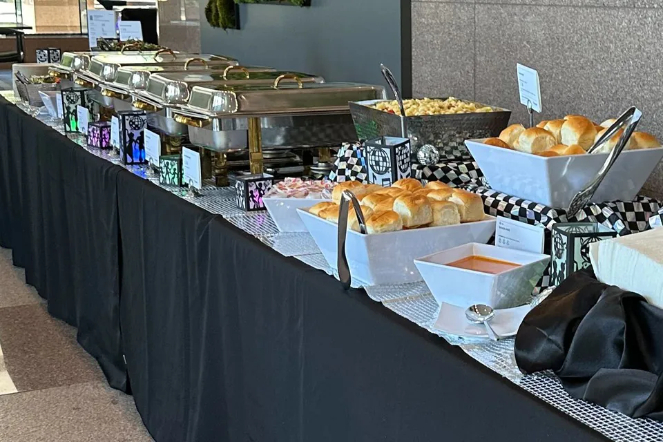 Hot office catering buffet line with chafing dishes, dinner rolls, macaroni and cheese, and soup