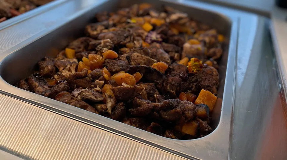 Hotel pan of spice-rubbed roasted chicken with butternut squash on an office buffet counter