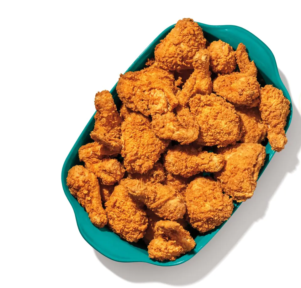 Overhead view of a teal catering tray holding twenty five pieces of fried chicken in mixed cuts including drumsticks, thighs, breasts and wings