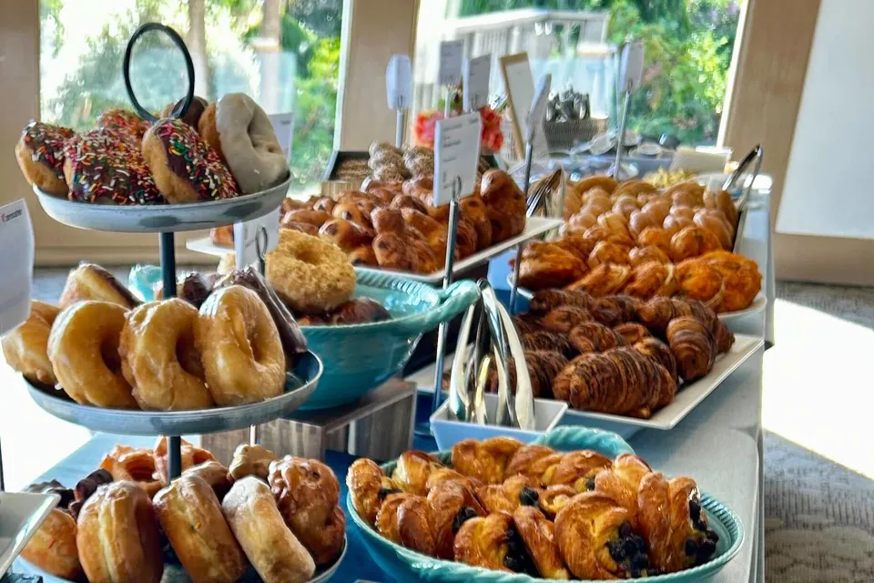 A bakery-cafe breakfast spread on a Zerocater office table Croissants, pastries and doughnuts on tiered trays at an office breakfast