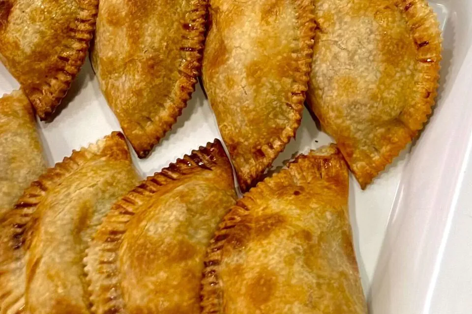 Baked empanadas on a white platter