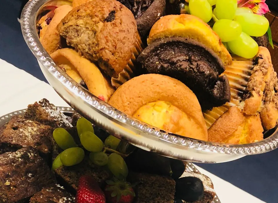 Tiered silver tray of muffins, brownies, pastries and fresh fruit on a catering table
