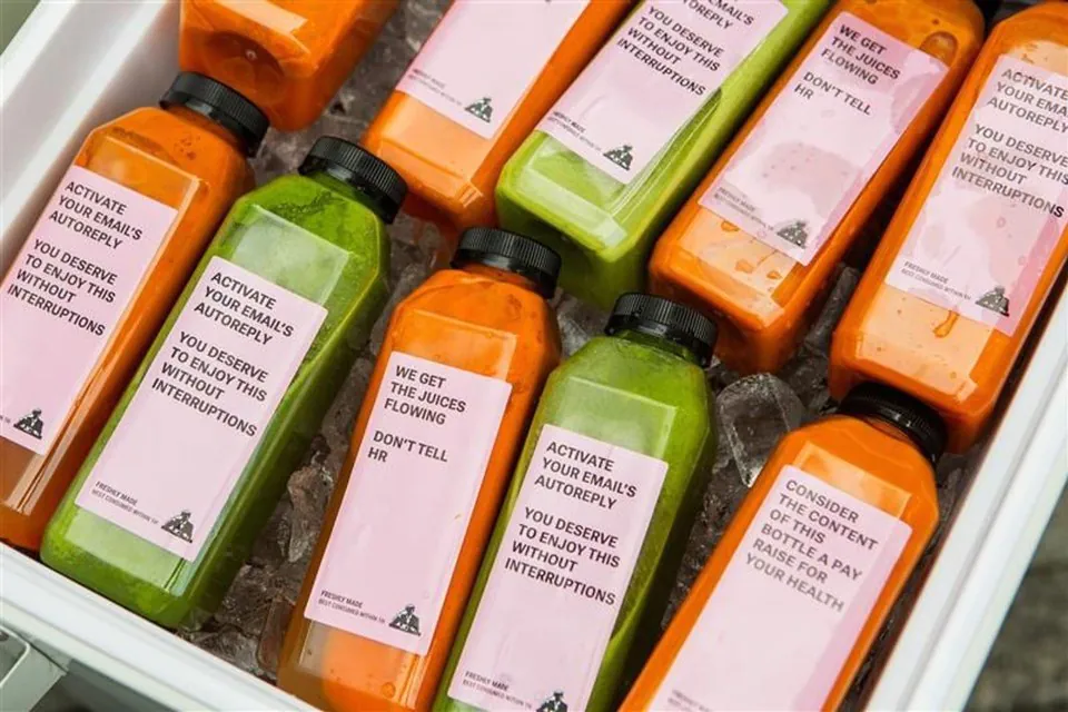 Bottles of green and orange juice packed upright in ice inside a white cooler