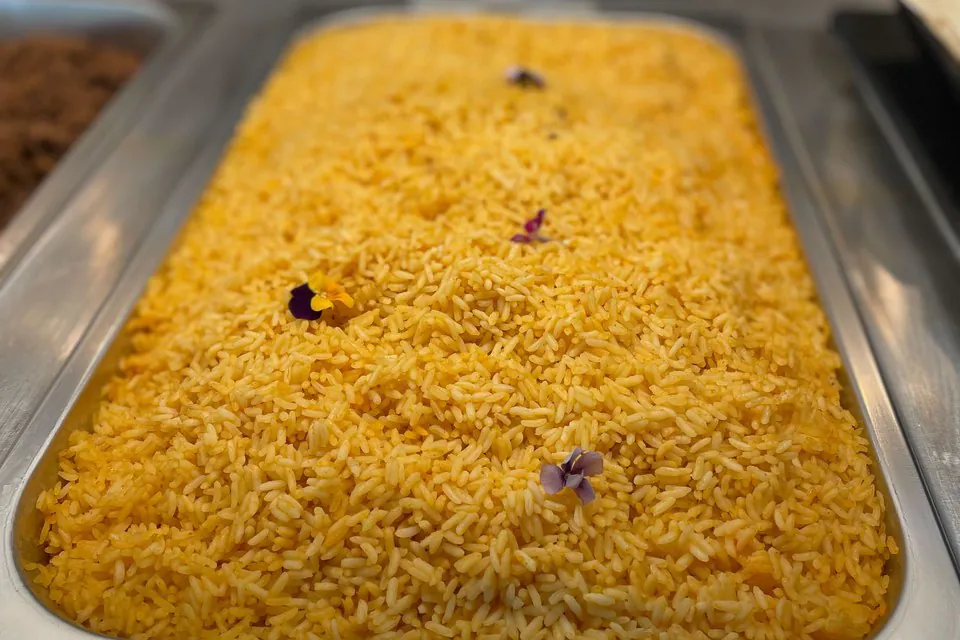 Saffron rice in a catering pan Full catering pan of saffron yellow rice garnished with edible flowers