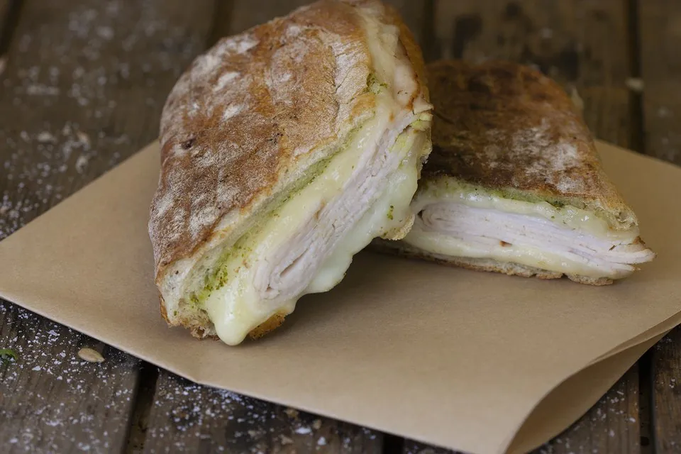 A hot pressed sandwich from The Picnic Basket A hot pressed turkey sandwich on toasted ciabatta, cut in half to show turkey, melted Swiss cheese and basil pesto
