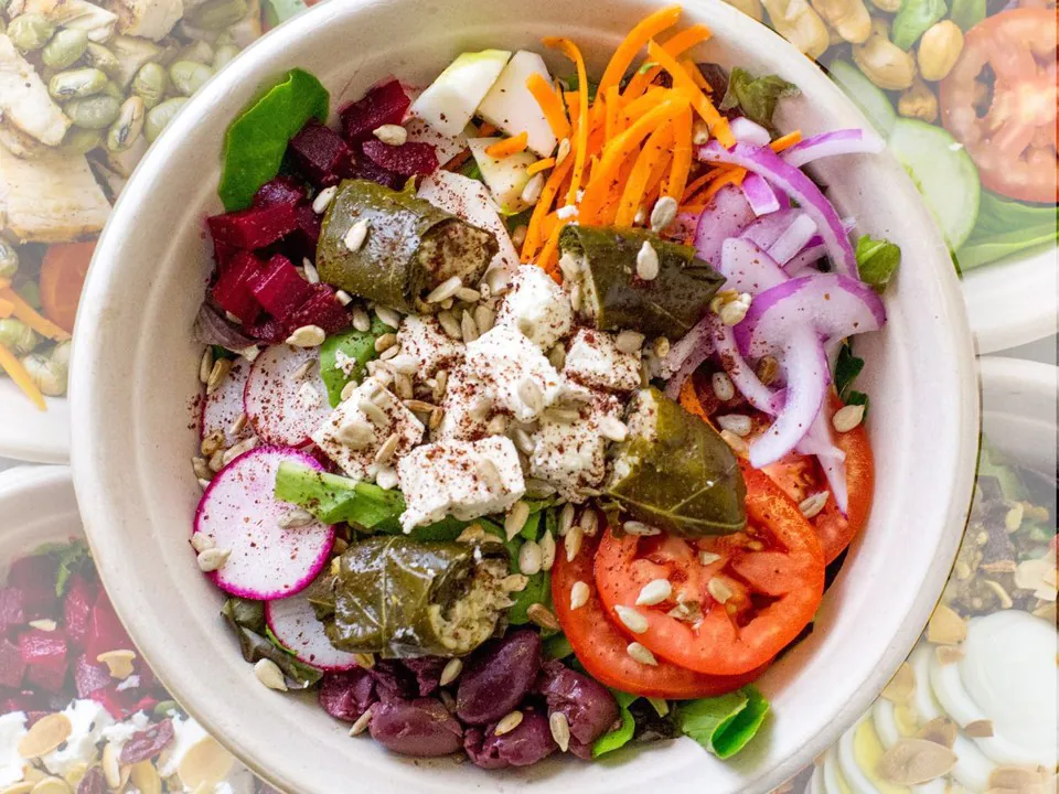 The Root Vegetables and Feta salad A round bowl of the root vegetables and feta salad, with beets, radish, carrots, red onion, feta, stuffed vine leaves and kalamata olives over greens