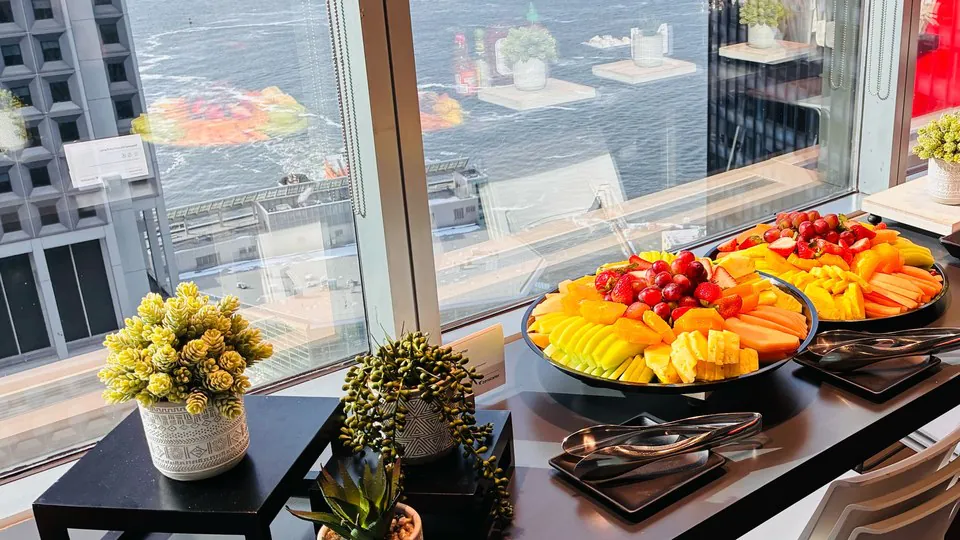 Two large fruit platters set out on an office counter beside a window