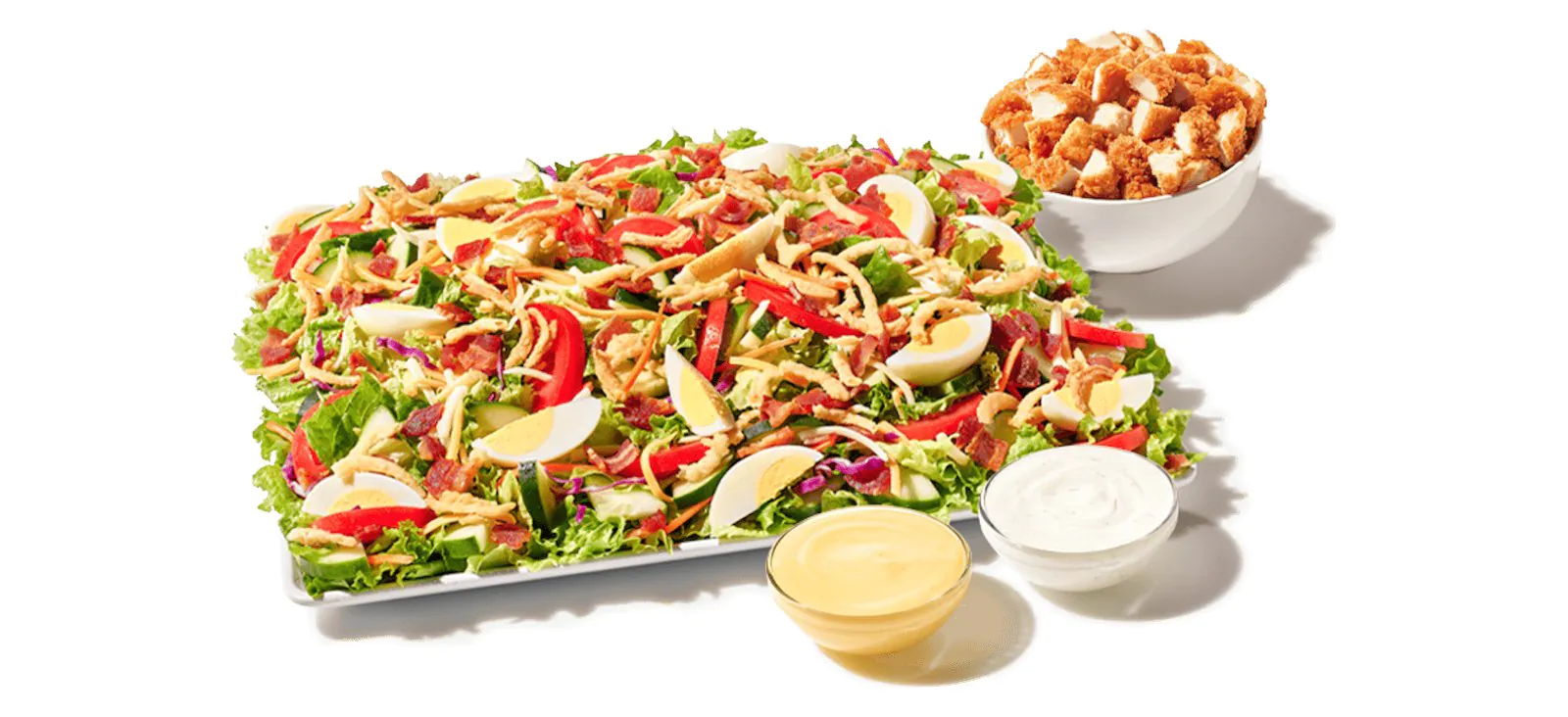 A Zaxby's Cobb Zalad Platter of mixed greens, tomatoes, hard-boiled egg, bacon and fried onions, with a bowl of fried chicken pieces and two cups of dressing