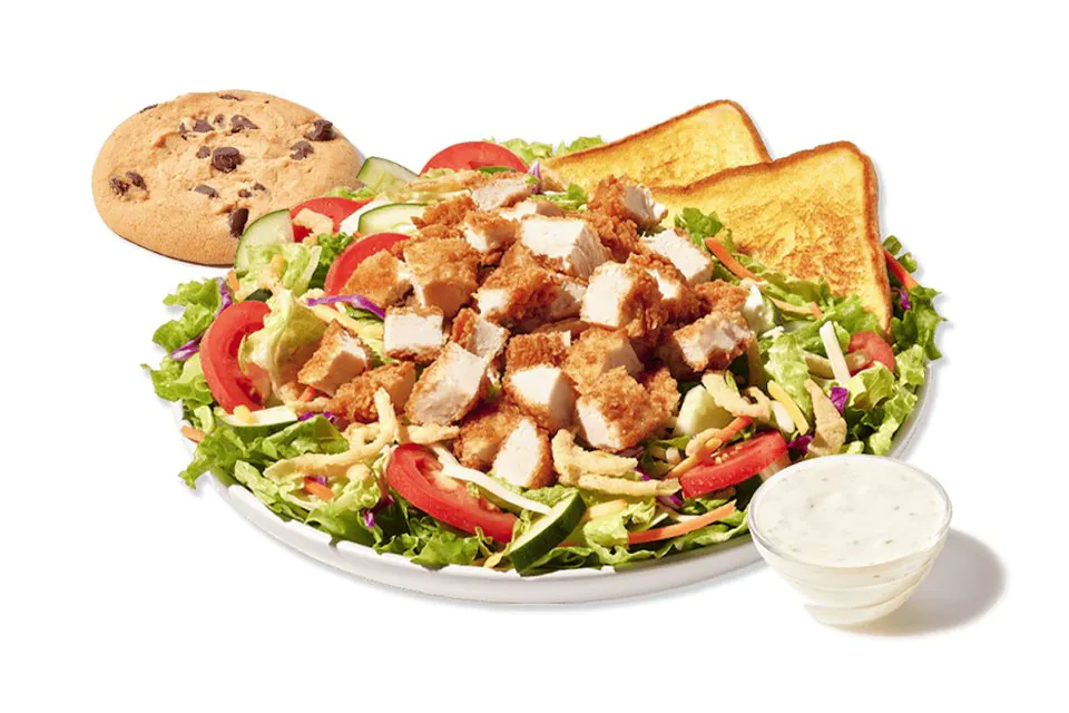 A Zaxby's House Zalad boxed lunch of greens, tomatoes and fried chicken pieces with two slices of Texas Toast, a chocolate chip cookie and a cup of Ranch